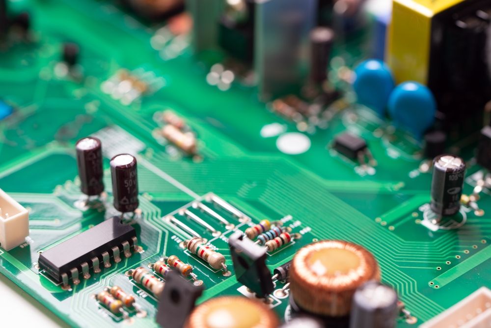 A detailed view of a green PCB showing inductors, capacitors, resistors, headers, and an IC. The image shows various electronic components used in power regulation and signal processing.