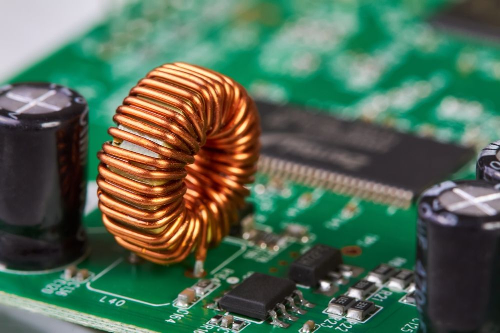 Orange inductor with copper wire on green printed circuit board detail