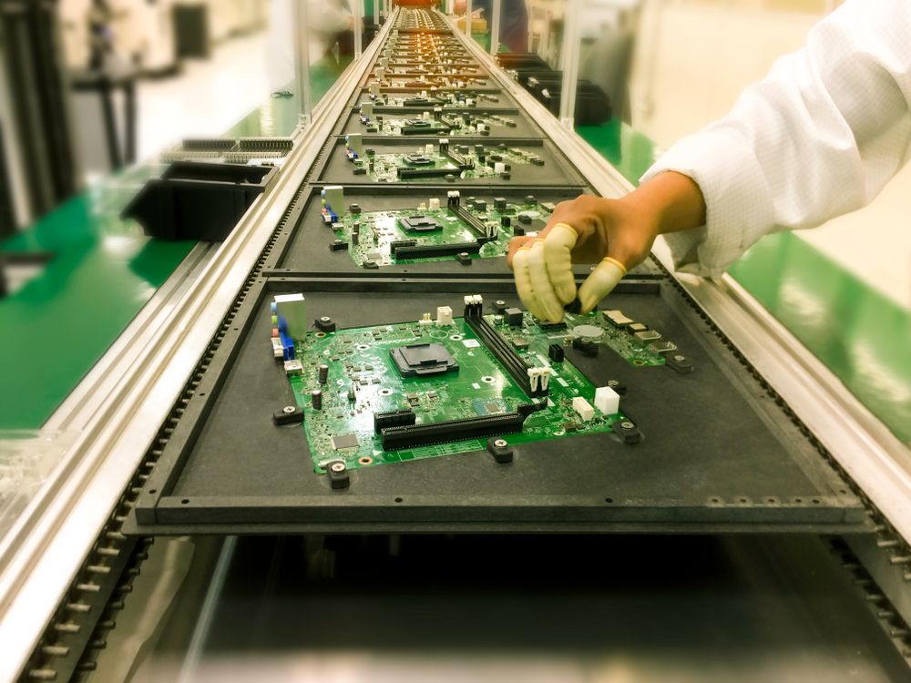 image not focus of hands manual insertion of electronic components on printing circuit board assembly before wave soldering. in a electronic production plat on a conveyor belt.,blurred background