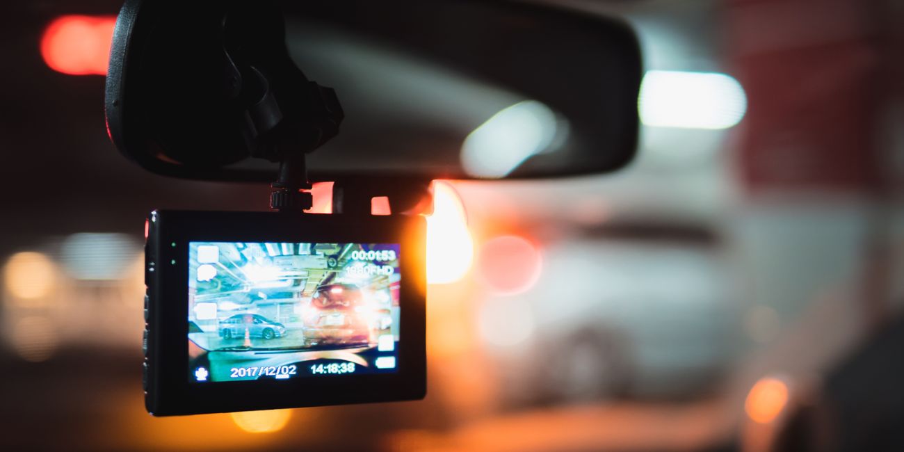 A dashcam mounted behind a car's rear-view mirror displaying a 1080p night-time recording of road traffic, representing an automotive camera application that relies on high-performance ADC signal chains.